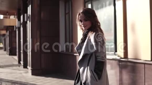迷人的年轻女子穿着外套微笑着穿过秋天的城市现代社会背景下的可爱女孩视频的预览图