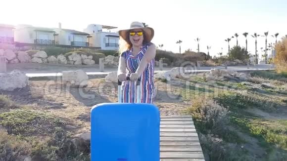 带着手提箱戴帽子度假的快乐年轻女人视频的预览图