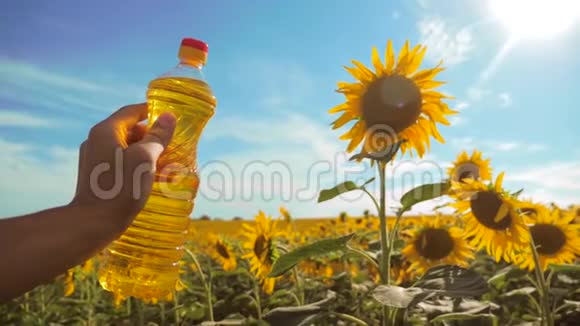 慢动作录像生活方式男人农民手里拿着一瓶葵花籽油在日落时的田野里农民农业视频的预览图