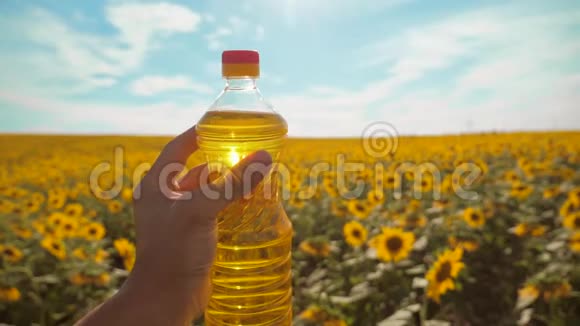 农夫手里拿着一个塑料瓶生活方式是葵花籽油在他的手里的阳光下慢动作视频蓝天视频的预览图