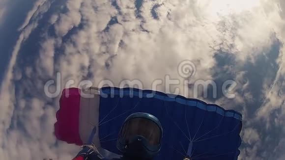跳伞者戴着头盔跳伞在多云的天空中晴天极限运动速度视频的预览图