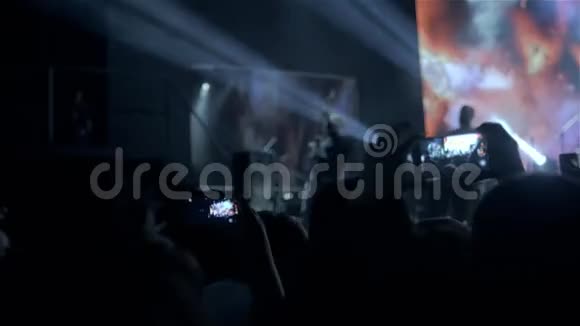 在音乐节上观众举起双手灯光从舞台上方流下来摇滚表演视频的预览图