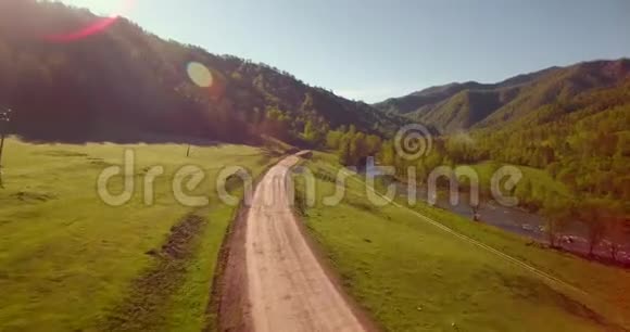 在阳光明媚的夏日早晨中气飞越新鲜的山河和草地农村土路下面视频的预览图