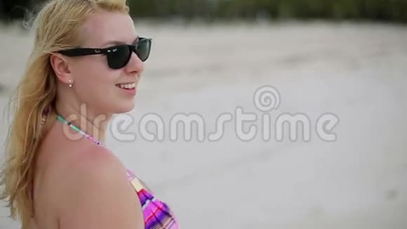 穿比基尼在沙滩上散步的年轻女子视频的预览图