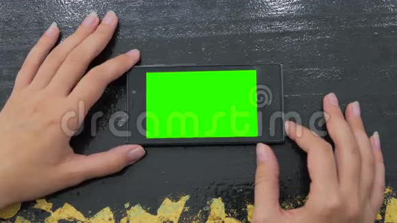 女人看着绿色屏幕的智能手机视频的预览图