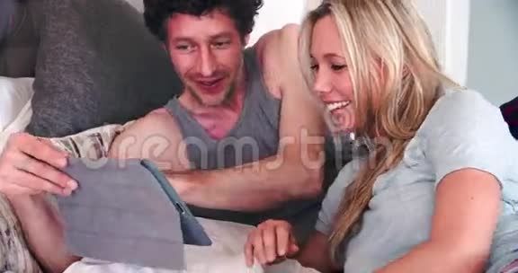 使用数码平板电脑躺在床上的情侣视频的预览图