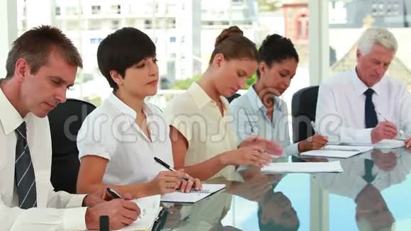 商务人士坐在会议桌前做笔记视频的预览图