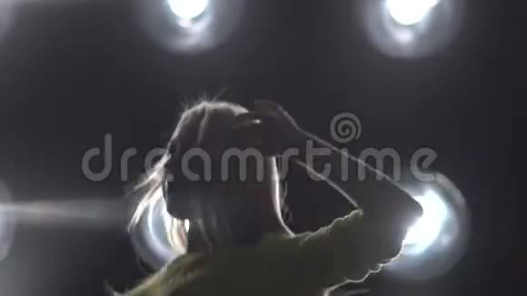 一个女孩在背景灯上跳舞的剪影视频的预览图