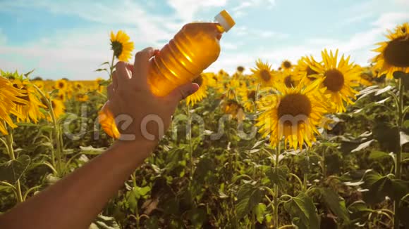 农夫手里拿着一瓶生活方式塑料的向日葵油在他的手里的阳光下慢动作视频蓝天视频的预览图