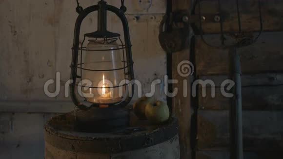 晚上农夫在一张有苹果的木桌上放了蜡烛的古玩灯带来了一盏灯和一盏灯视频的预览图