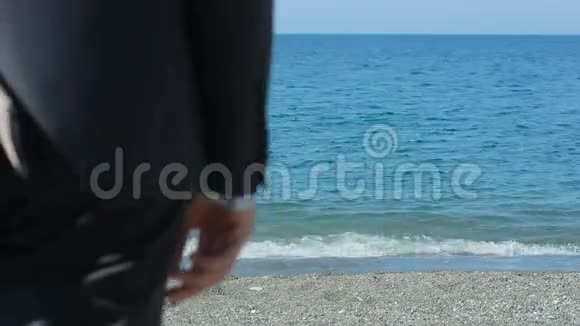 商人穿着西装在海滩上漫步欣赏美丽的海滩视频的预览图
