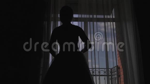 一个年轻的女人走近窗户打开阳台享受着早晨的新娘等待婚礼视频的预览图