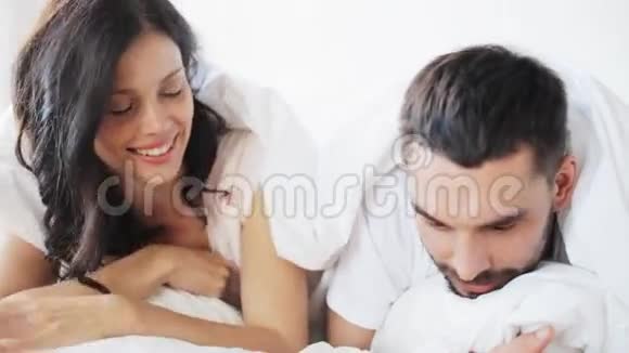 快乐的一对夫妇躺在家里的床上视频的预览图