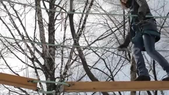 在极端公园的高绳道上年轻的女性登山者走在垂木桥旁视频的预览图