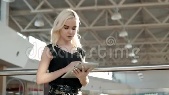 年轻的女乘客在机场等待航班时使用她的平板电脑美丽的女乘客在视频的预览图