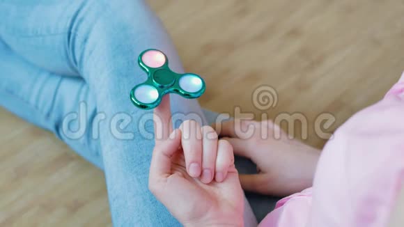 女孩在玩一个光滑的色彩鲜艳的手纺玩具视频的预览图