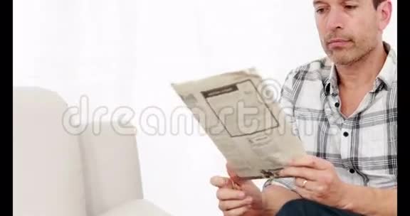 微笑的人坐在沙发上看报纸视频的预览图