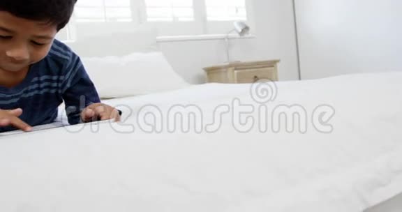 男孩在床上放松时使用数码平板电脑视频的预览图