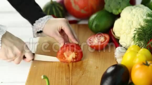 女人在新鲜蔬菜中切红番茄视频的预览图