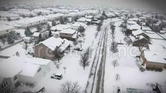 沿着郊区的街道飞过白雪覆盖的住宅和庭院视频的预览图