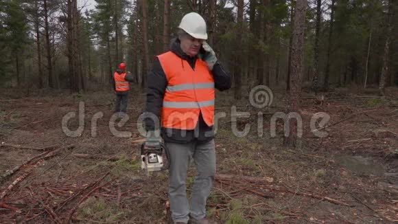 在森林里用电锯打电话的伐木工人视频的预览图