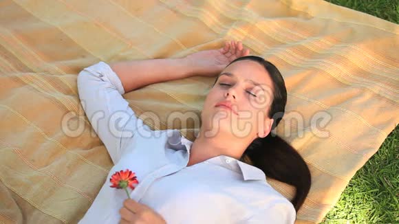 女人躺在户外拿着一朵花视频的预览图
