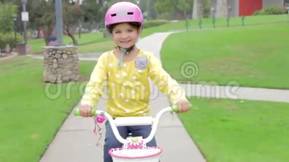 年轻女孩骑自行车在公园看镜头视频的预览图