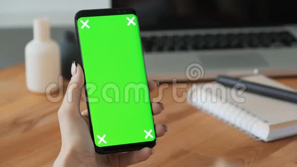 使用手机的人手拿绿色屏幕显示视频的预览图
