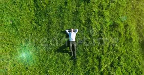 垂直运动飞越商人躺在新鲜的绿色草地上放松的人的最佳景观视频的预览图