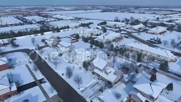 沿着郊区的街道飞过白雪覆盖的住宅和庭院视频的预览图