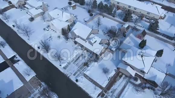 沿着郊区的街道飞过白雪覆盖的住宅和庭院视频的预览图