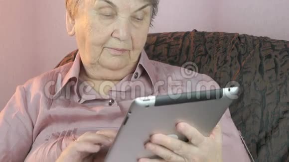 80多岁的老年妇女手持银制平板电脑视频的预览图