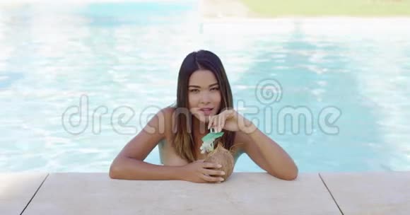 年轻漂亮的女人在度假泳池里放松视频的预览图