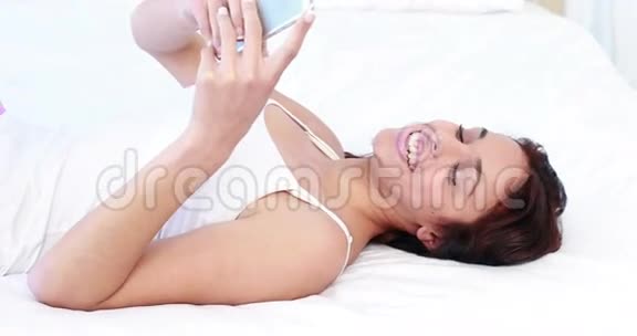 微笑的女人在床上发短信视频的预览图