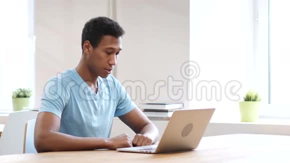 年轻的黑人在笔记本电脑上工作视频的预览图