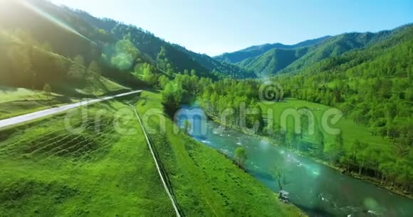 在阳光明媚的夏日早晨空中飞过新鲜的山河和草地农村土路下面视频的预览图