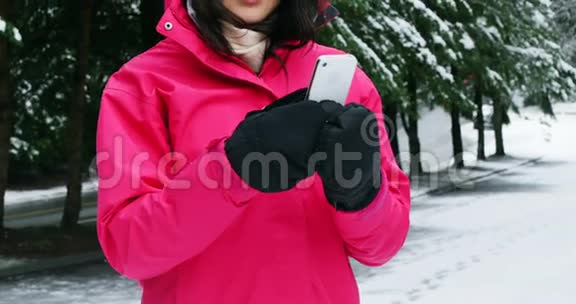 穿暖衣服的微笑女人用手机视频的预览图