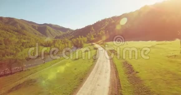 在阳光明媚的夏日早晨中气飞越新鲜的山河和草地农村土路下面视频的预览图