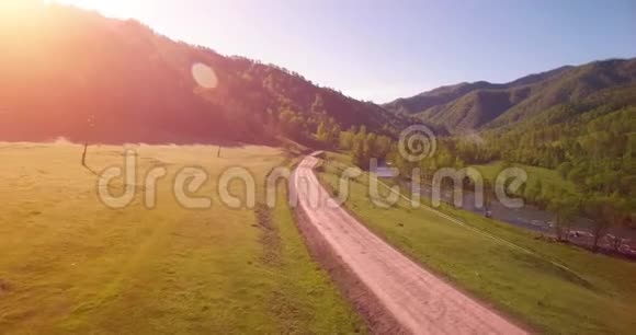 在阳光明媚的夏日早晨中气飞越新鲜的山河和草地农村土路下面视频的预览图