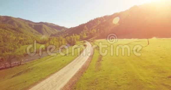 在阳光明媚的夏日早晨中气飞越新鲜的山河和草地农村土路下面视频的预览图