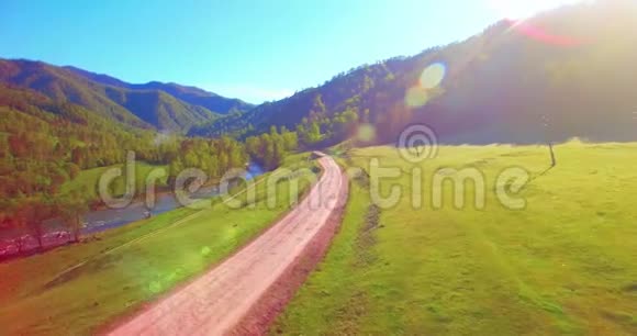 在阳光明媚的夏日早晨中气飞越新鲜的山河和草地农村土路下面视频的预览图