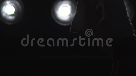 一个女孩在背景灯上跳舞的剪影慢动作视频的预览图
