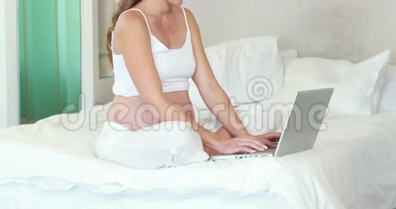 孕妇使用笔记本电脑在床上放松视频的预览图