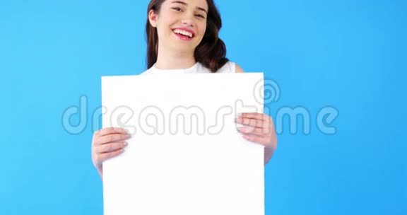 一位美丽的女士手里拿着蓝色背景的空白标语牌视频的预览图
