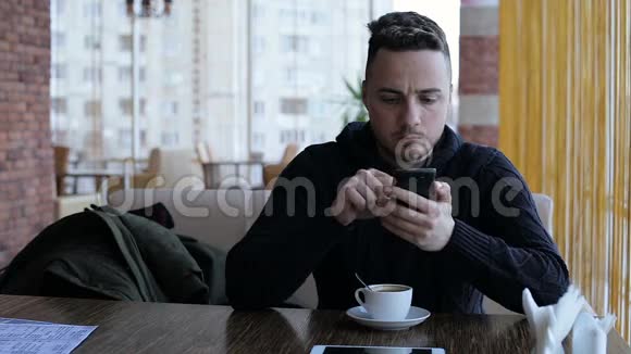 帅哥发短信在咖啡馆的智能手机上发短信视频的预览图