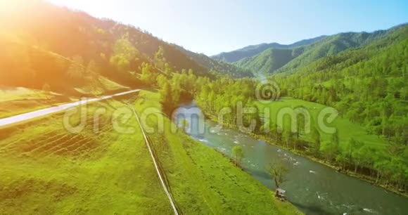 在阳光明媚的夏日早晨空中飞过新鲜的山河和草地农村土路下面视频的预览图