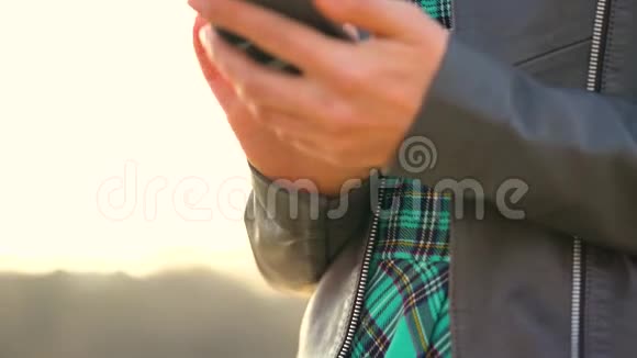 日落时分女人在户外使用智能手机视频的预览图