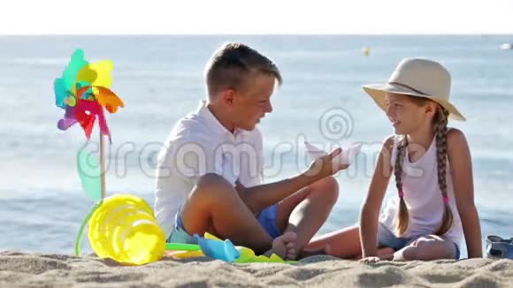 男孩和女孩坐在沙滩上视频的预览图