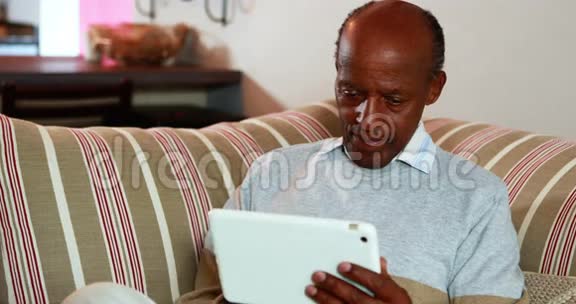 老人在家里客厅里使用数码平板电脑视频的预览图