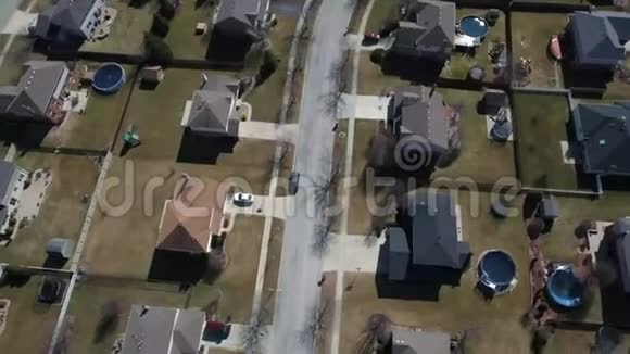 沿着郊区的街道飞过白雪覆盖的住宅和庭院视频的预览图